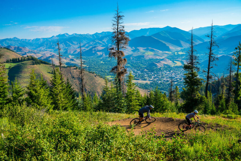 Two people biking down a trail on a sunny day at Sun Valley Resort